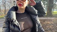 Beautiful woman shows her big breasts while walking in the park