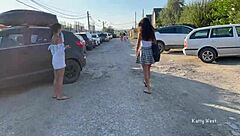 Two girls tease in public, flashing pussies without panties, small tits bouncing outdoors.