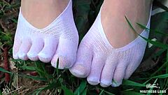 Cute toes in white socks on a spring grass field