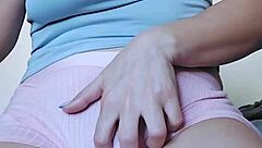 A solo girl masturbates, rubbing her pink pussy with her fingers