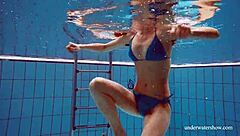 A girl in a blue bikini tightly takes a guy underwater in the pool