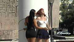A red-haired girl is having fun with her girlfriend in public place