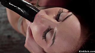 座ったボンデージのブロネットがタイトロープで指マンと焦らされるドミパートナーに