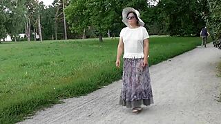 Kone strutter i gennemsigtig kjole gennem offentlig park